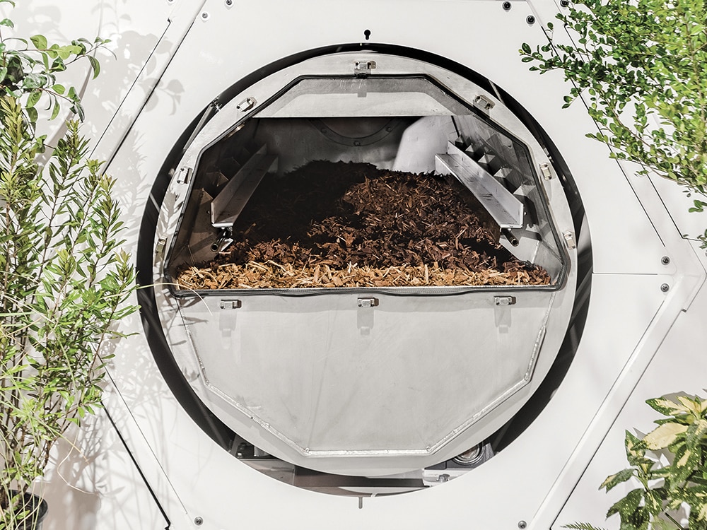 An open vessel with wood chips to show how human composting works