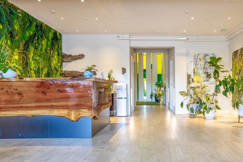 lobby of green funeral home filled with lush plants and wood live edge desk